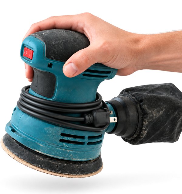 A hand holding an orbital sander with its cord wrapped around it